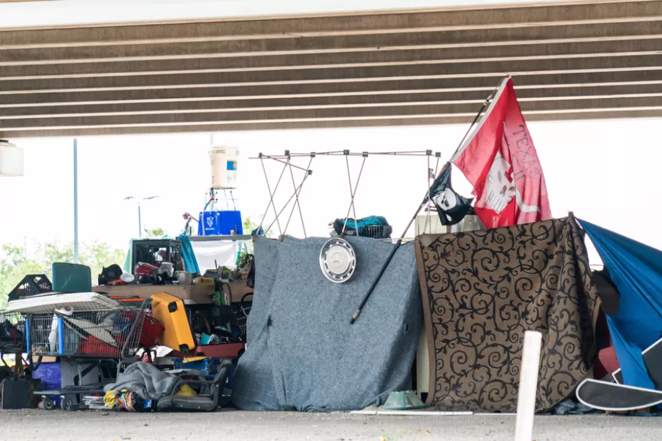 Encampment of unhoused people with tents and draped fabrics in Austin, Texas
